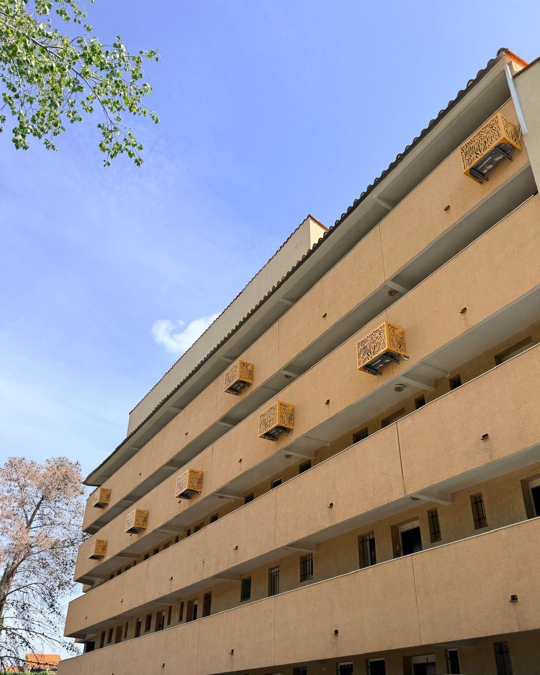 Vue d'ensemble de la façade d'une résidence équipée de cache-clim sur mesure