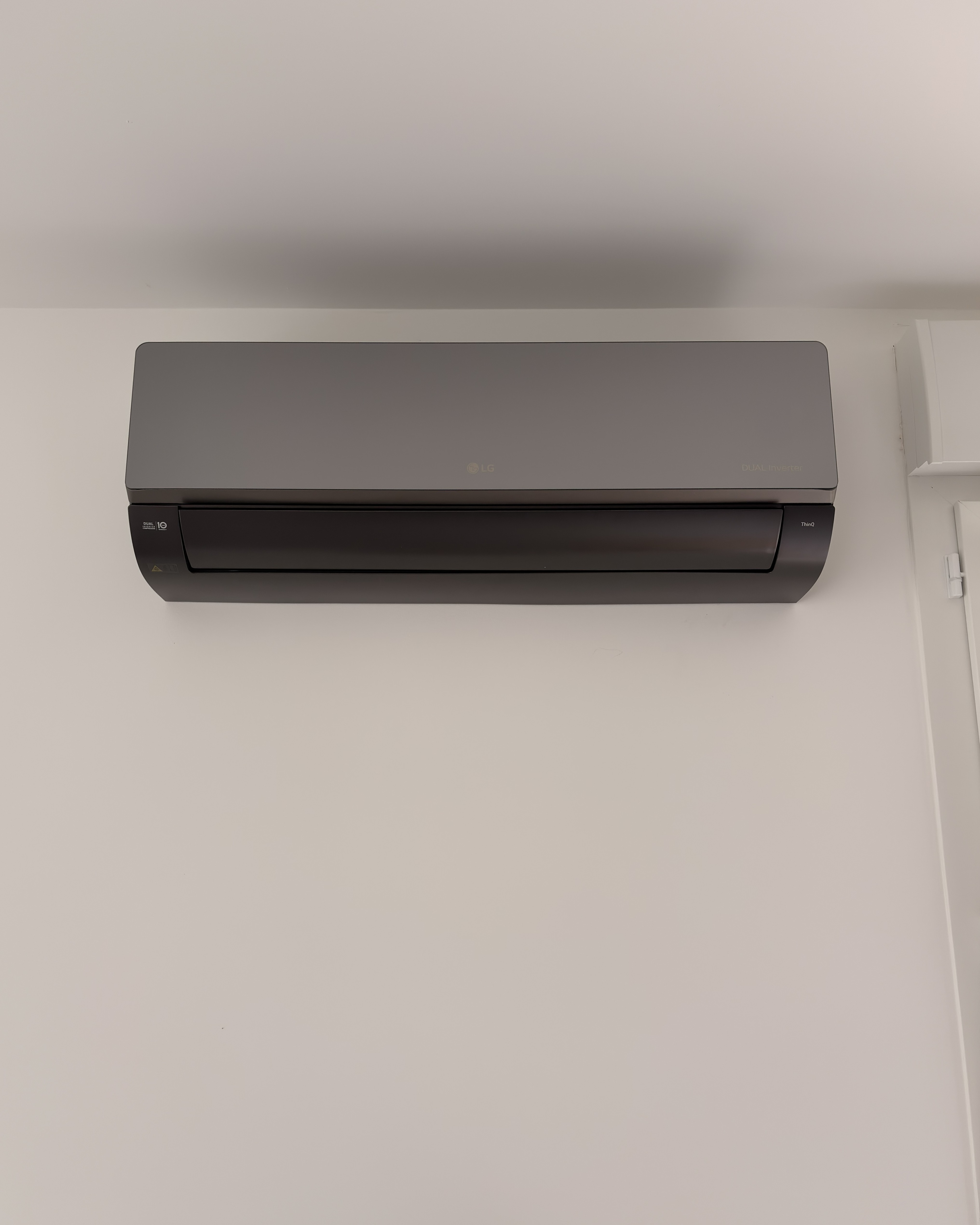 Unité murale de climatisation LG Mirror au design miroir noir, installée au plafond d'une pièce