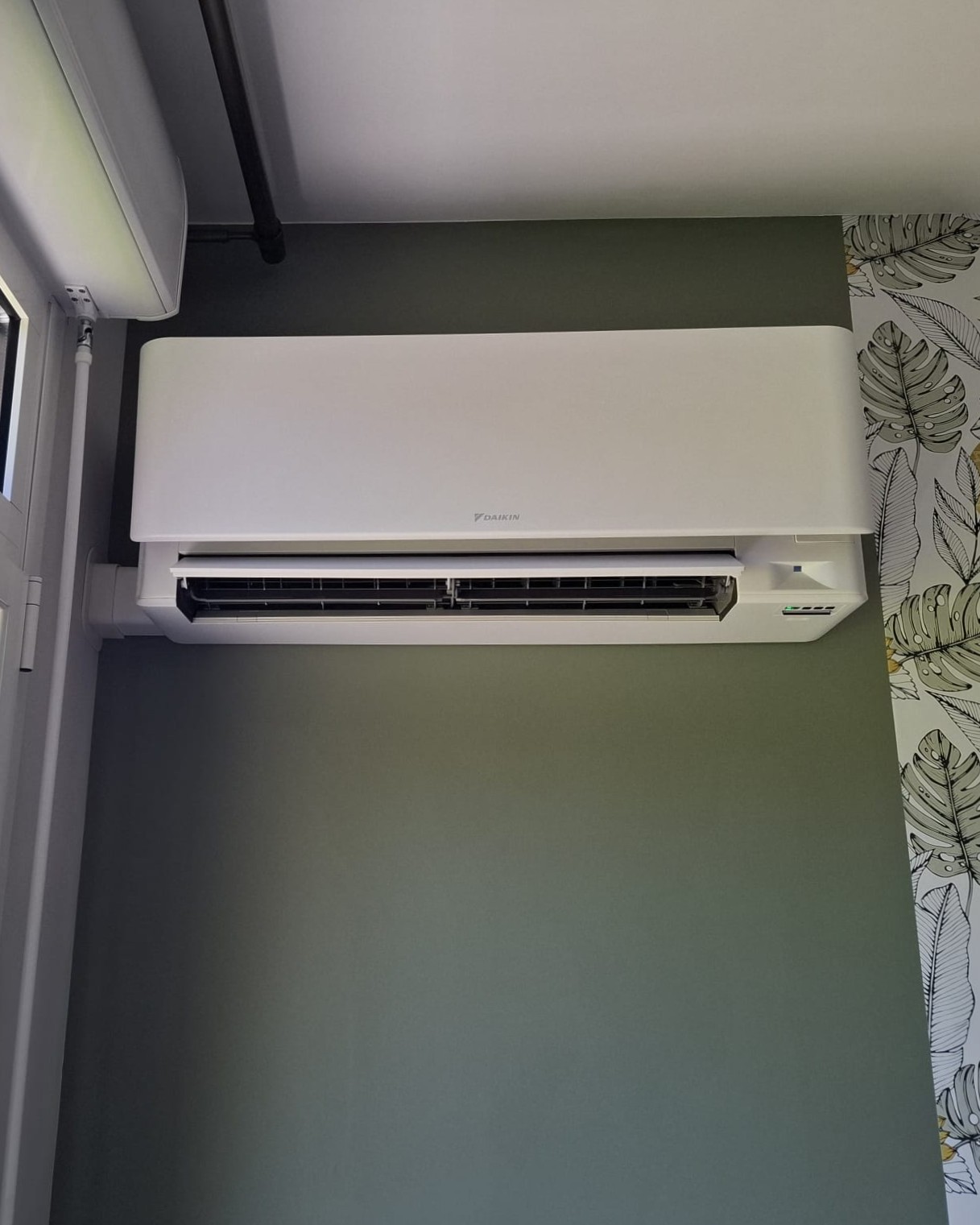 Unité murale Daikin Stylish blanche installée dans une chambre au mur vert